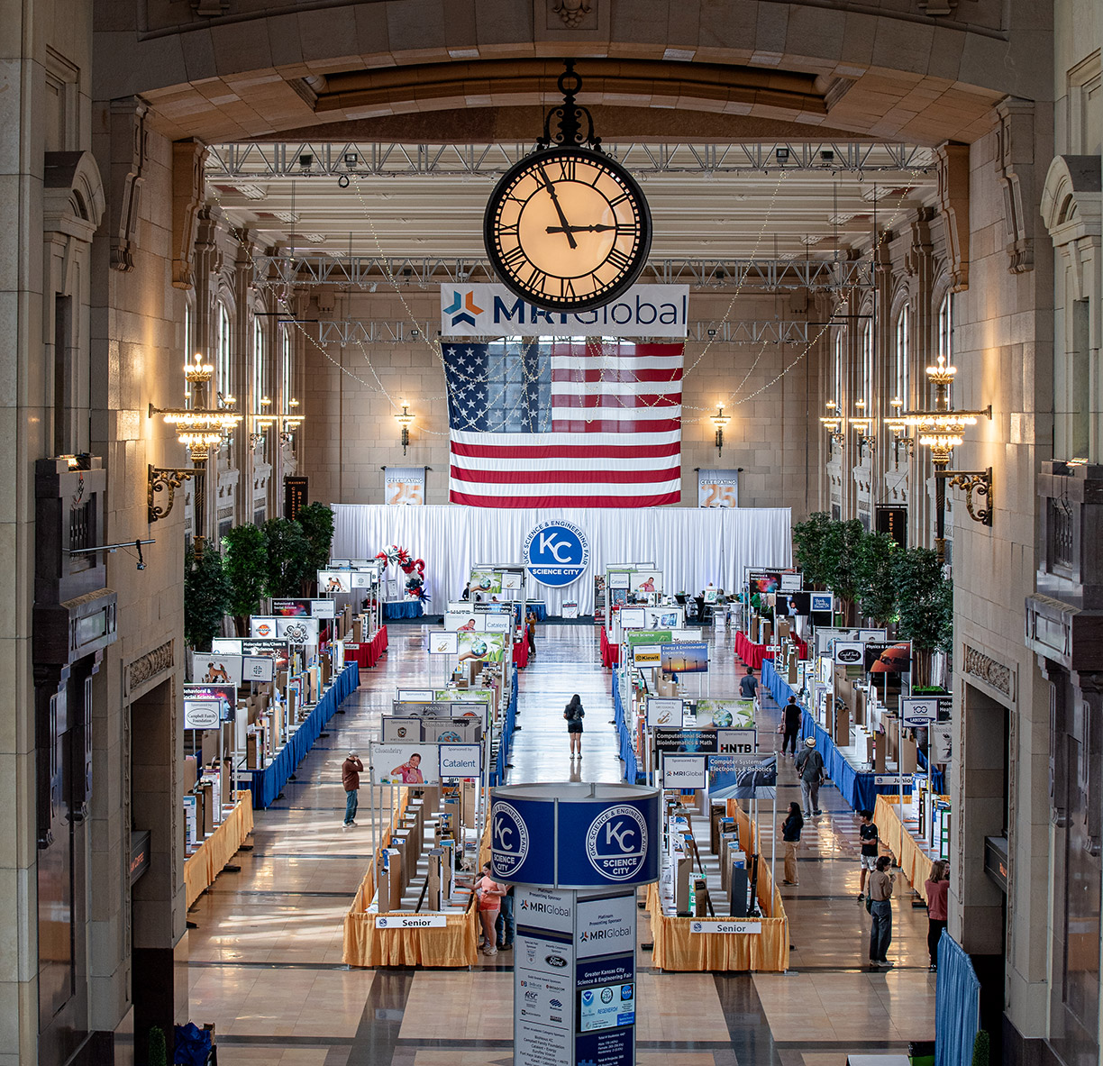 A photo from the 2025 Greater Kansas City Science and Engineering Fair. Showing a long hall filled with tables and projects.