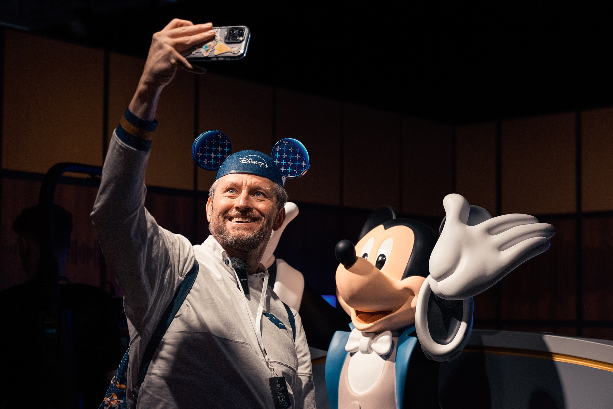 Man takes a selfie with Mickey Mouse at Disney100: The Exhibition