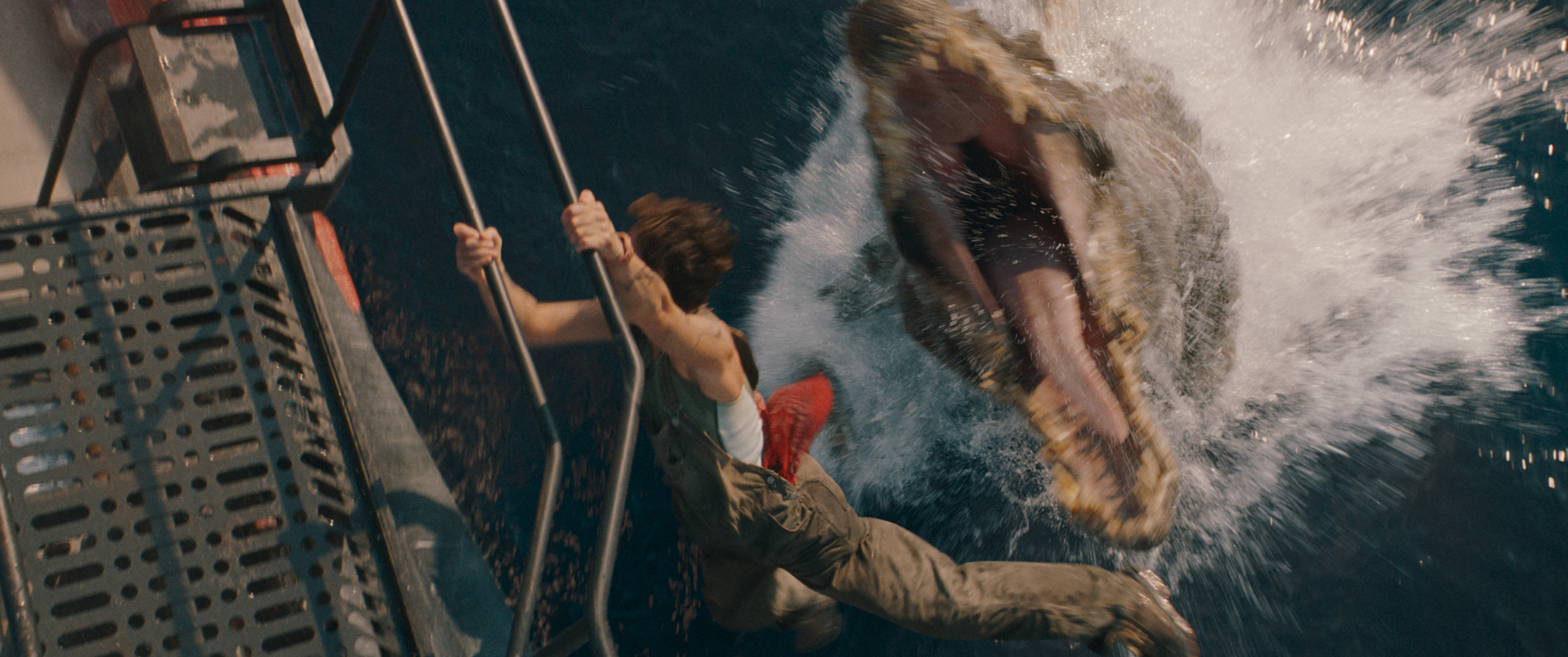 Image from Jurassic World Rebirth showing a dinosaur jumping out of the water towards a character hanging off a boat.