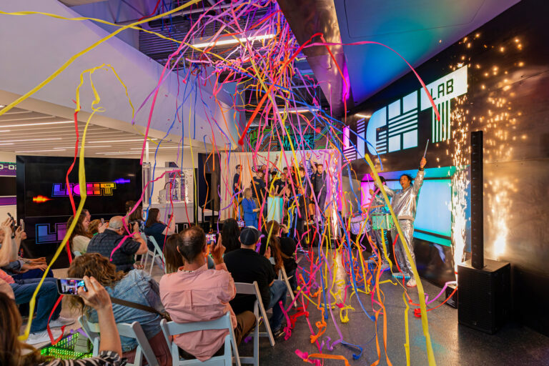 This image shows the grand opening of light lab. In the background are the winning students on stage, with confetti and indoor fireworks around them.