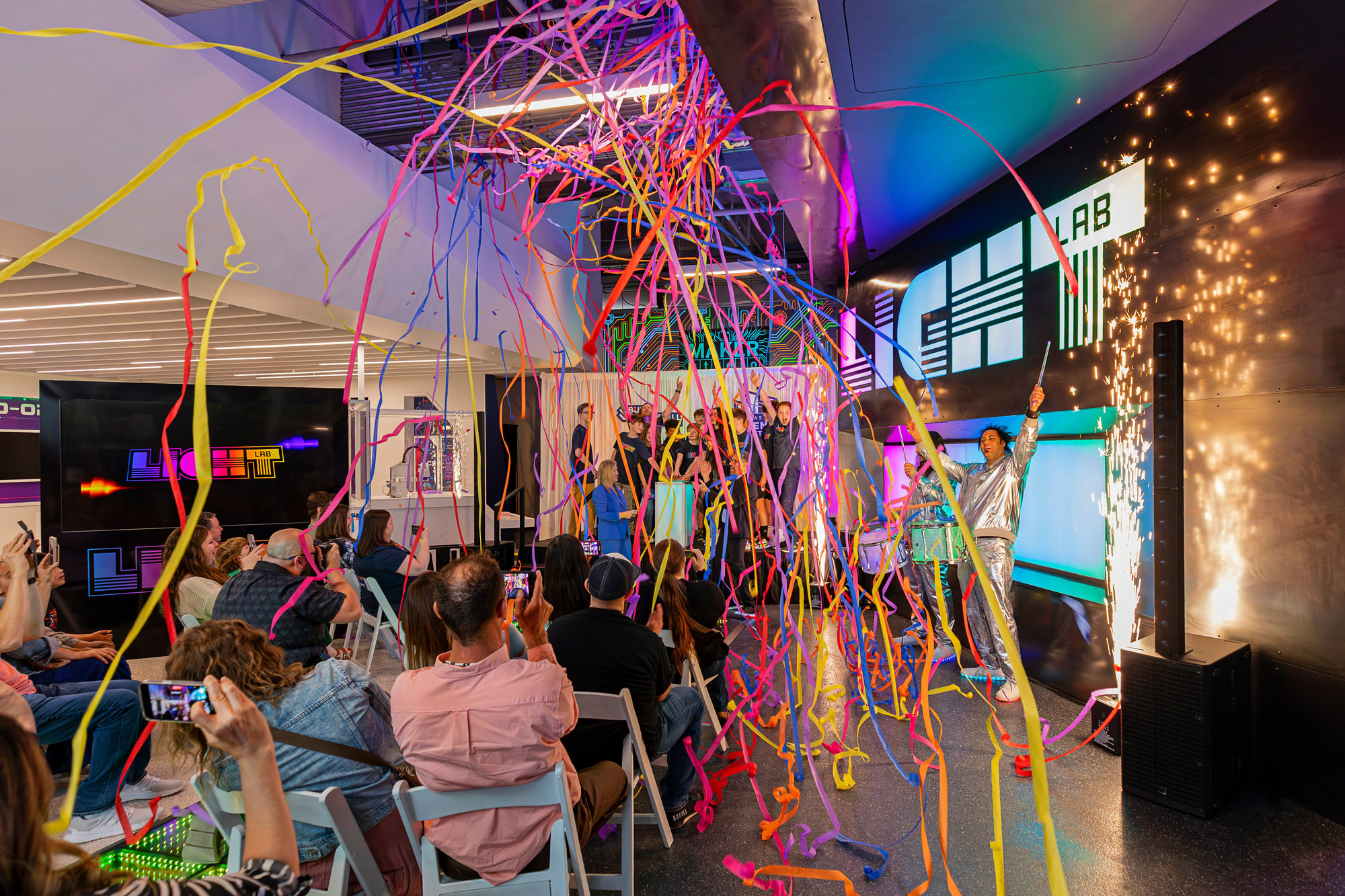 This image shows the grand opening of light lab. In the background are the winning students on stage, with confetti and indoor fireworks around them.