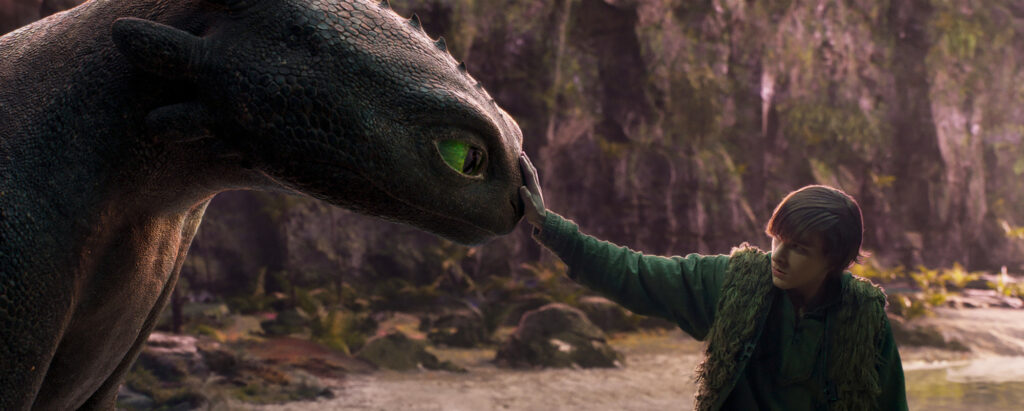 This image shows Hiccup with his hand on the dragon Toothless' nose.