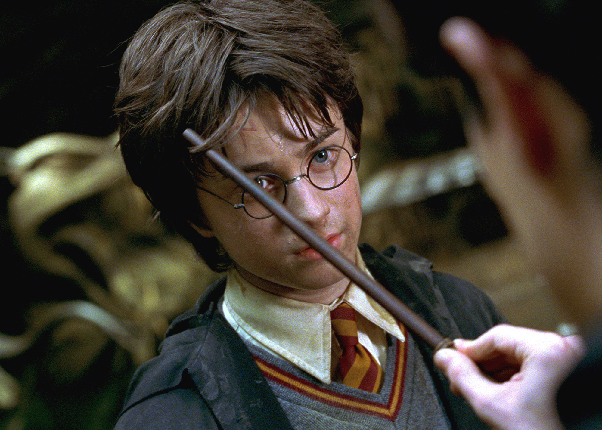 Promo image from Harry Potter and the Chamber of Secrets showing Harry Potter facing off with another student with a wand in his face.