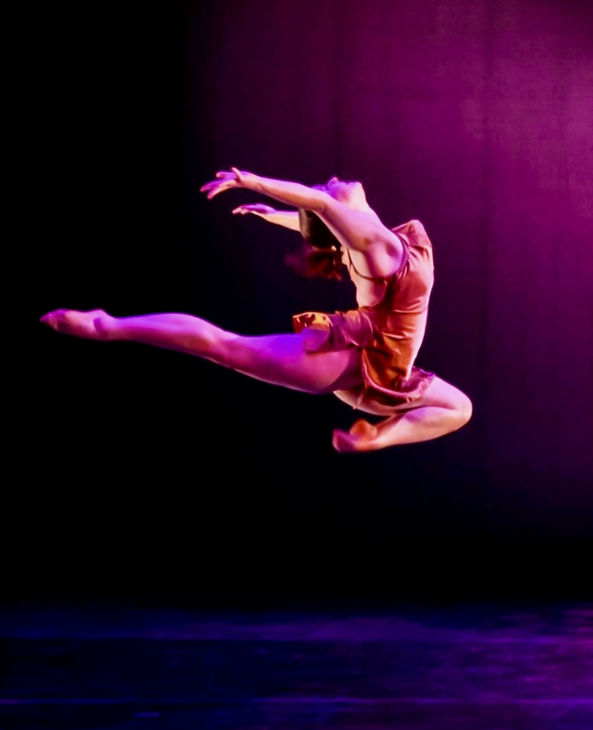 Photo from a performance of Prism, showing a dancer as she leaps through the air.