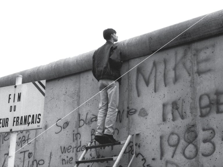 Man looking over the top of the Berlin wall
