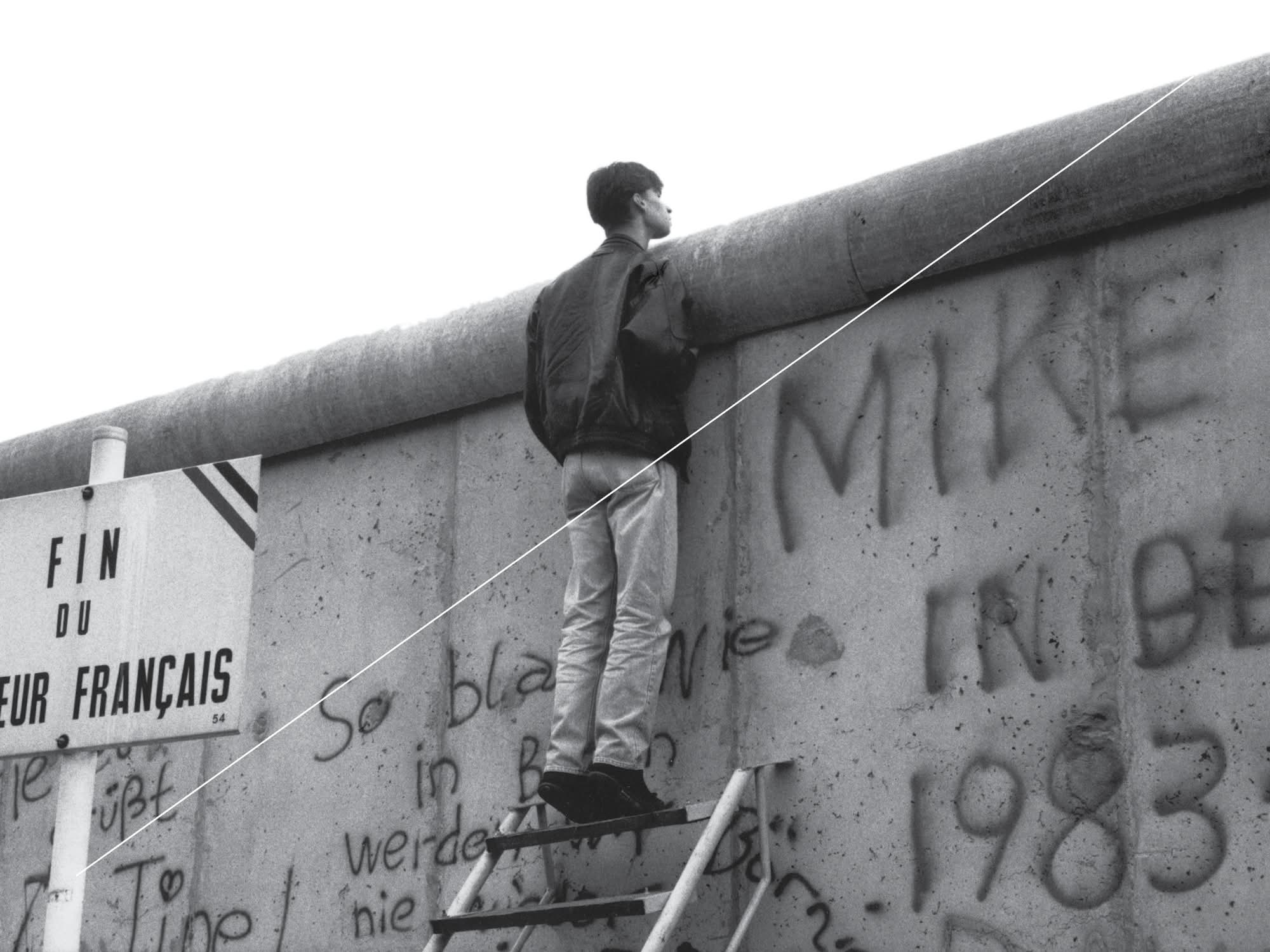 Man looking over the top of the Berlin wall