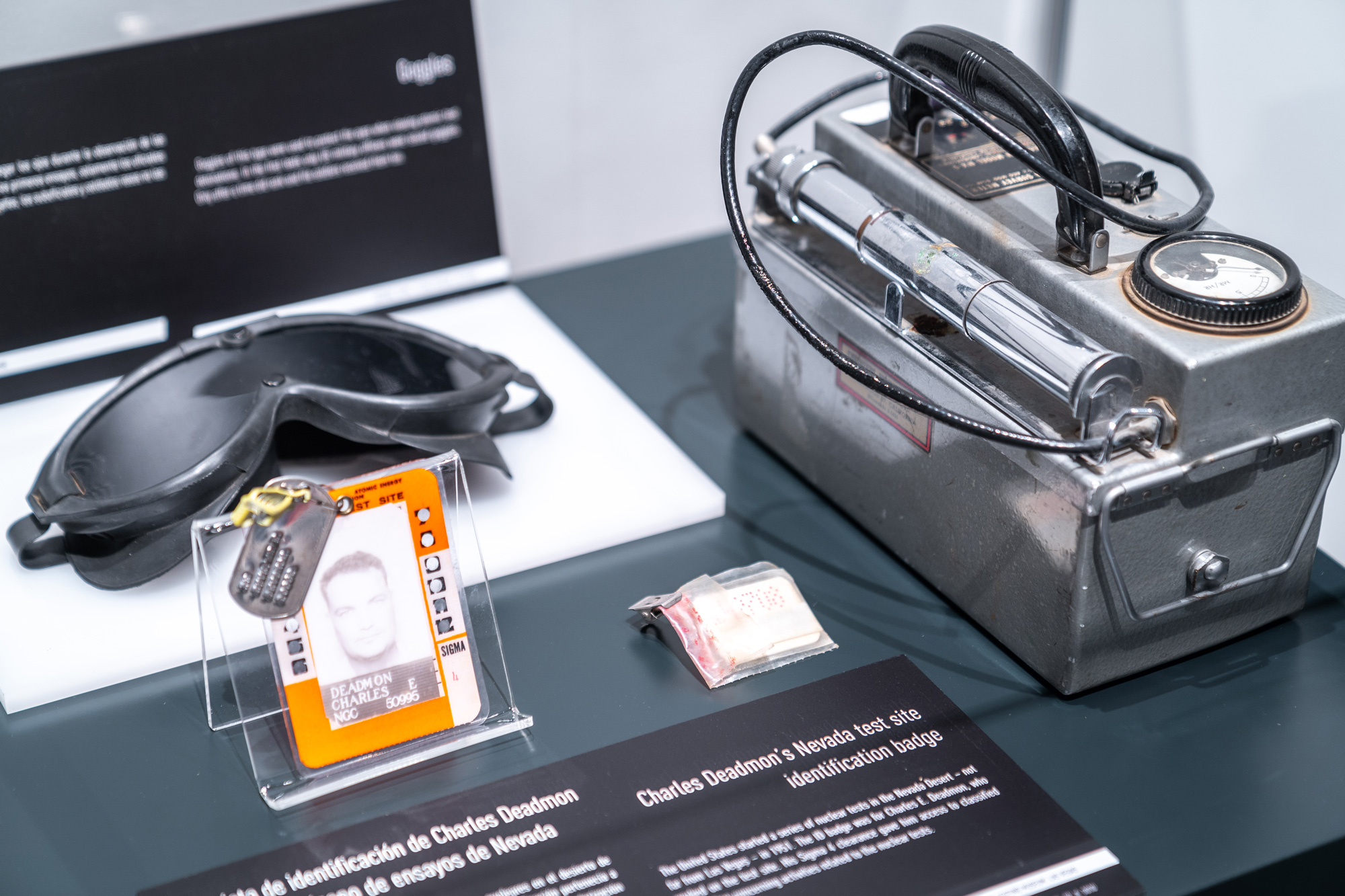 Various personal equipment used by a US employee including a work badge, mask, and gieger counter that displayed inside of The Berlin Wall. A World Divided.