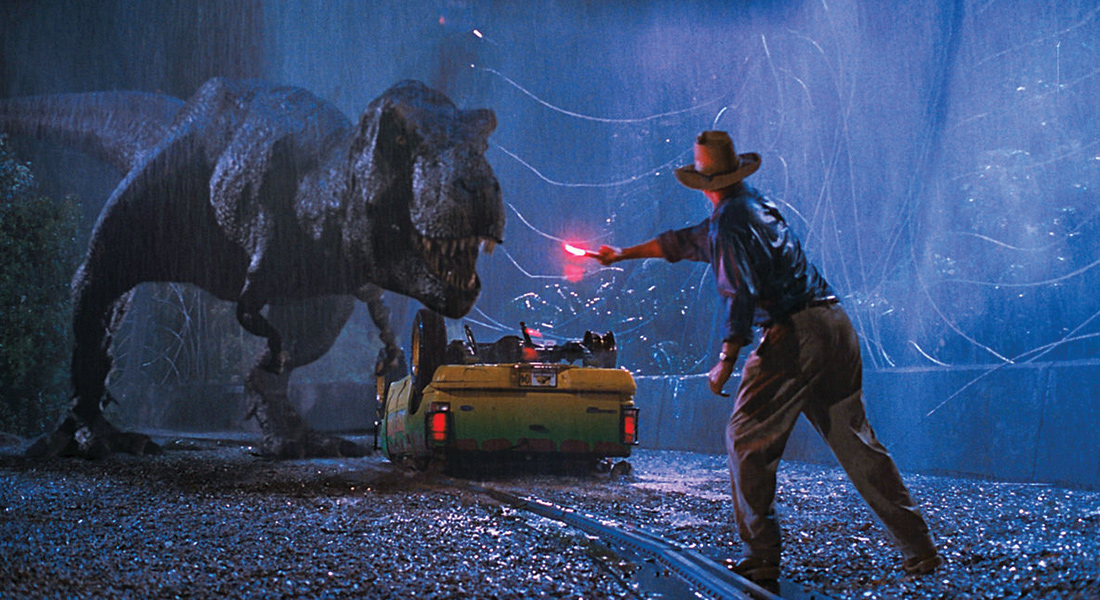 A still image from Jurassic Park. Featuring the character Grant as he attempts to distract a T-Rex using a flair.
